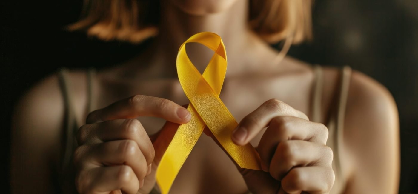 Close-up photo of a person holding a yellow ribbon, suitable for use in promotions or as a symbol of support